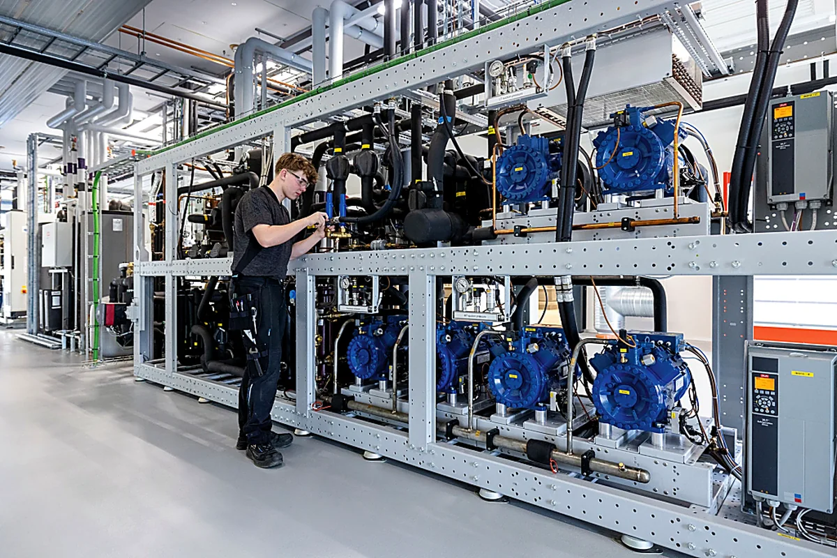 Technician inspecting a commercial CO2 refrigeration compressor rack